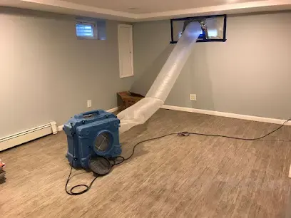 Air scrubber with ducting venting a finished basement during a water damage dry-out in Queens