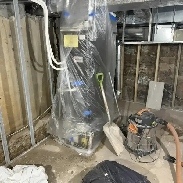 Plastic containment around a furnace and a wet vacuum in a cellar during cleanup in Queens