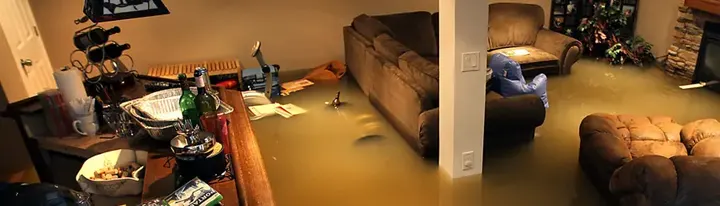 Deep water across a flooded finished basement with furniture after a storm in Queens