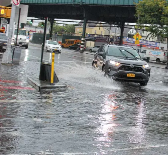 Flooded street under elevated train tracks in Queens during a heavy downpour